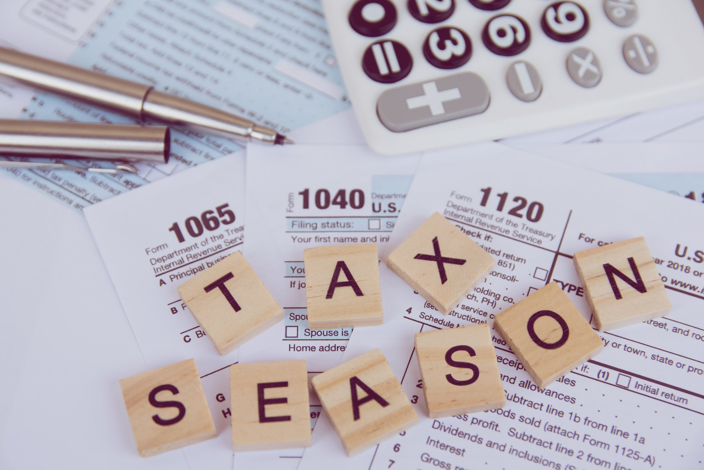 Tax season with wooden alphabet blocks, calculator, pen on 1040 tax form background